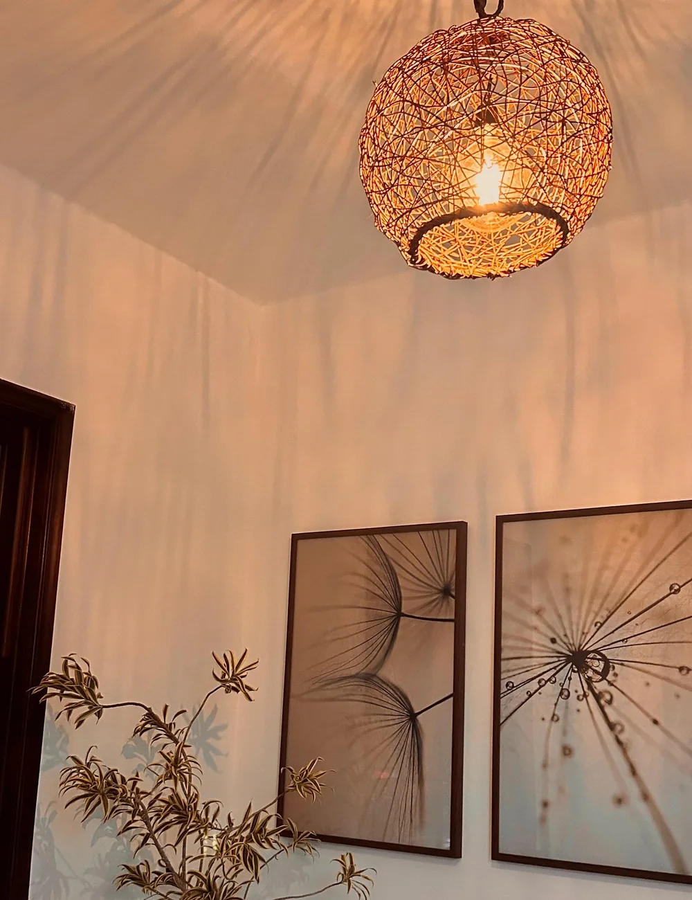 Recepção do Ágape ao entardecer: luminária de fibras acesa, quadros botânicos, planta e sofá claro.