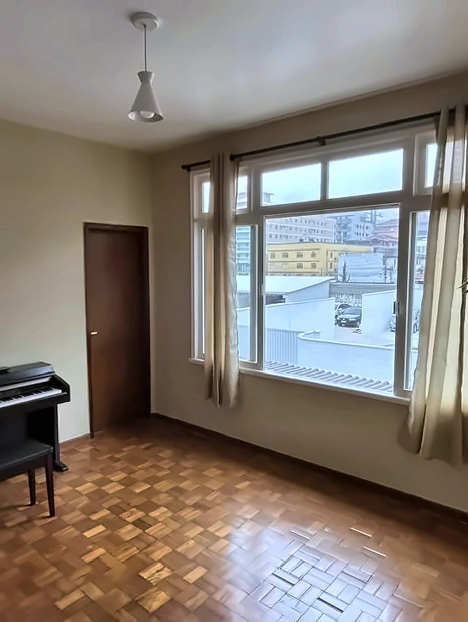 Sala coletiva com piano, plantas e janelas amplas.