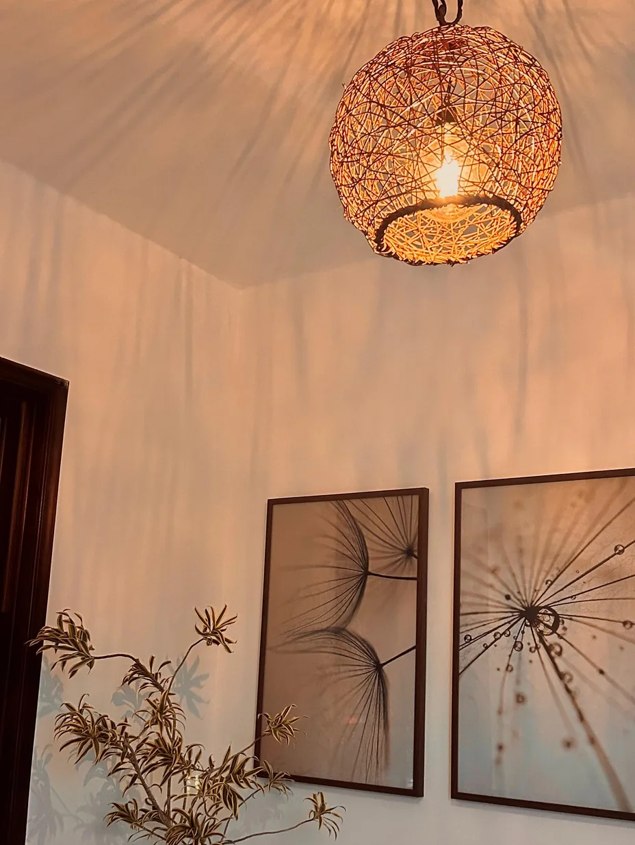 Recepção do Ágape ao entardecer: luminária de fibras acesa, quadros botânicos, planta e sofá claro.