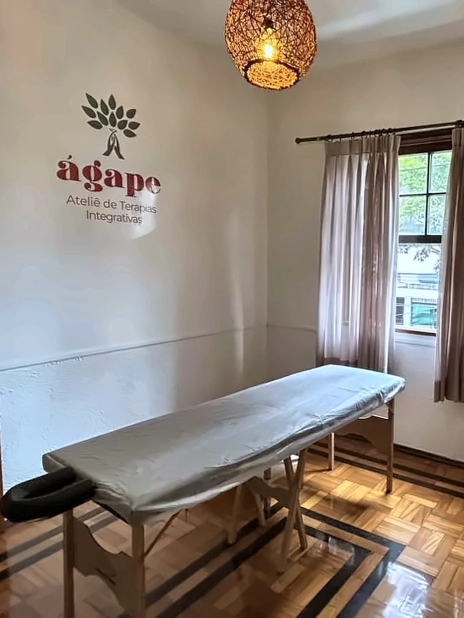 Sala de terapias integrativas com maca e a marca do Ágape na parede.