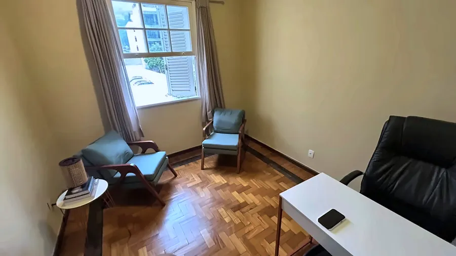 Poltronas azuis junto à janela, com mesa de apoio.