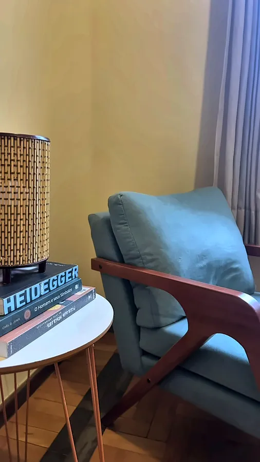 Detalhe: poltrona, mesinha com livros e luminária.
