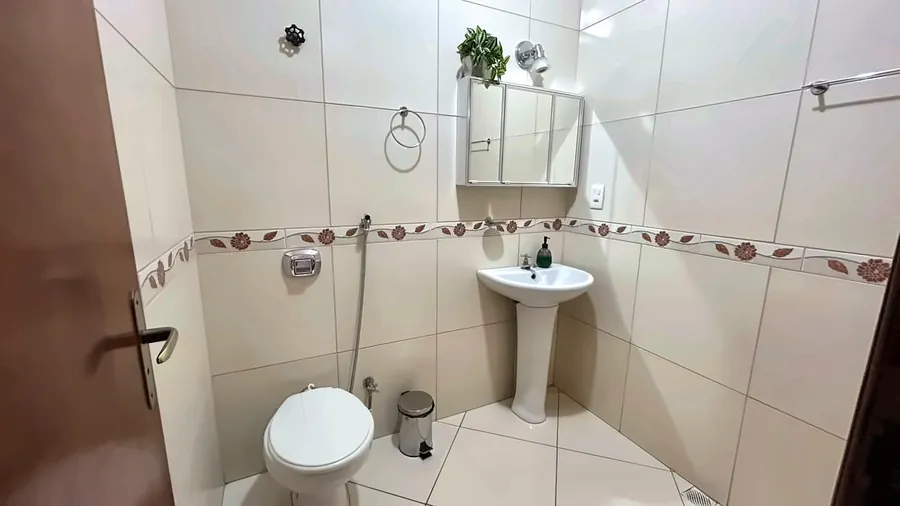 Banheiro com pia de coluna e faixa decorada.