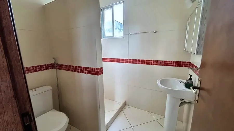 Banheiro com faixa vermelha e janela.