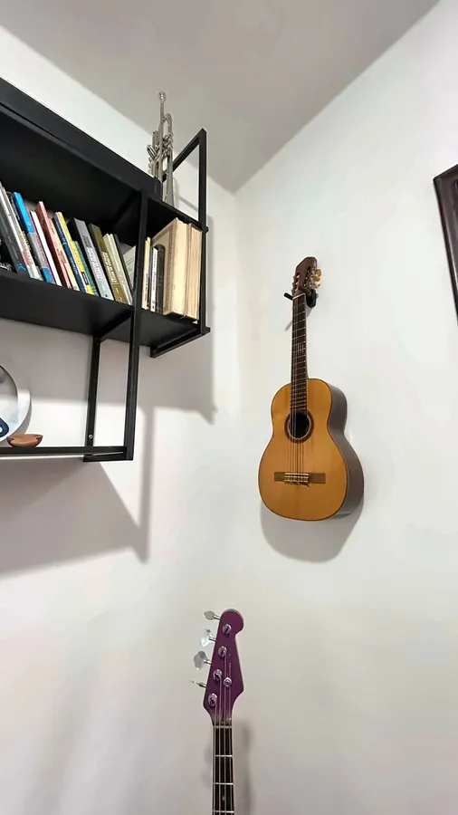 Detalhe: estante de livros e violão na parede.