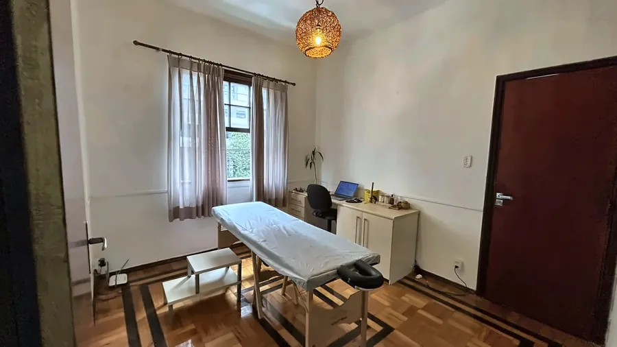 Outro ângulo da sala de terapia, com a maca e a porta.